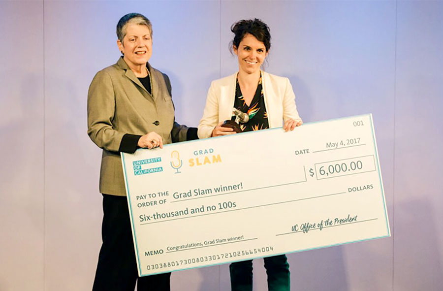 Grad Slam 2017 winner Leslie Rith-Najarian stands holding a giant check with her winnings, next to University of California President Janet Napolitano